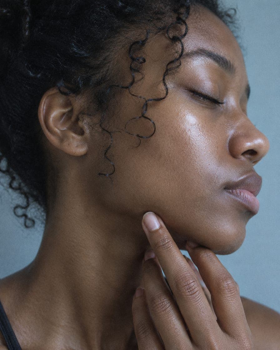 A woman with her eyes closed resting her fingertips along her jaw